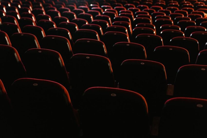 Rows of empty red seats in a dimly lit cinema hall